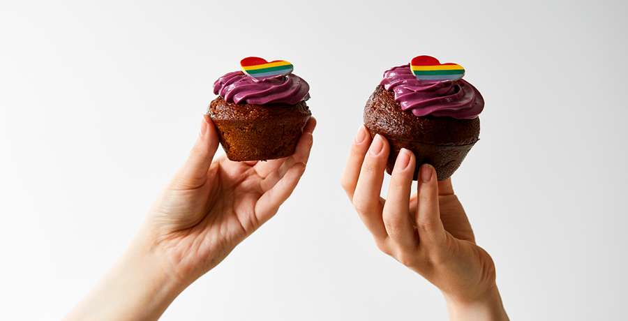 To Copenhagen Pride muffins lavet af Lagkagehuset, lavet af chokolade med ostecreme og et regnbuefarvet chokolade hjerte på toppen.